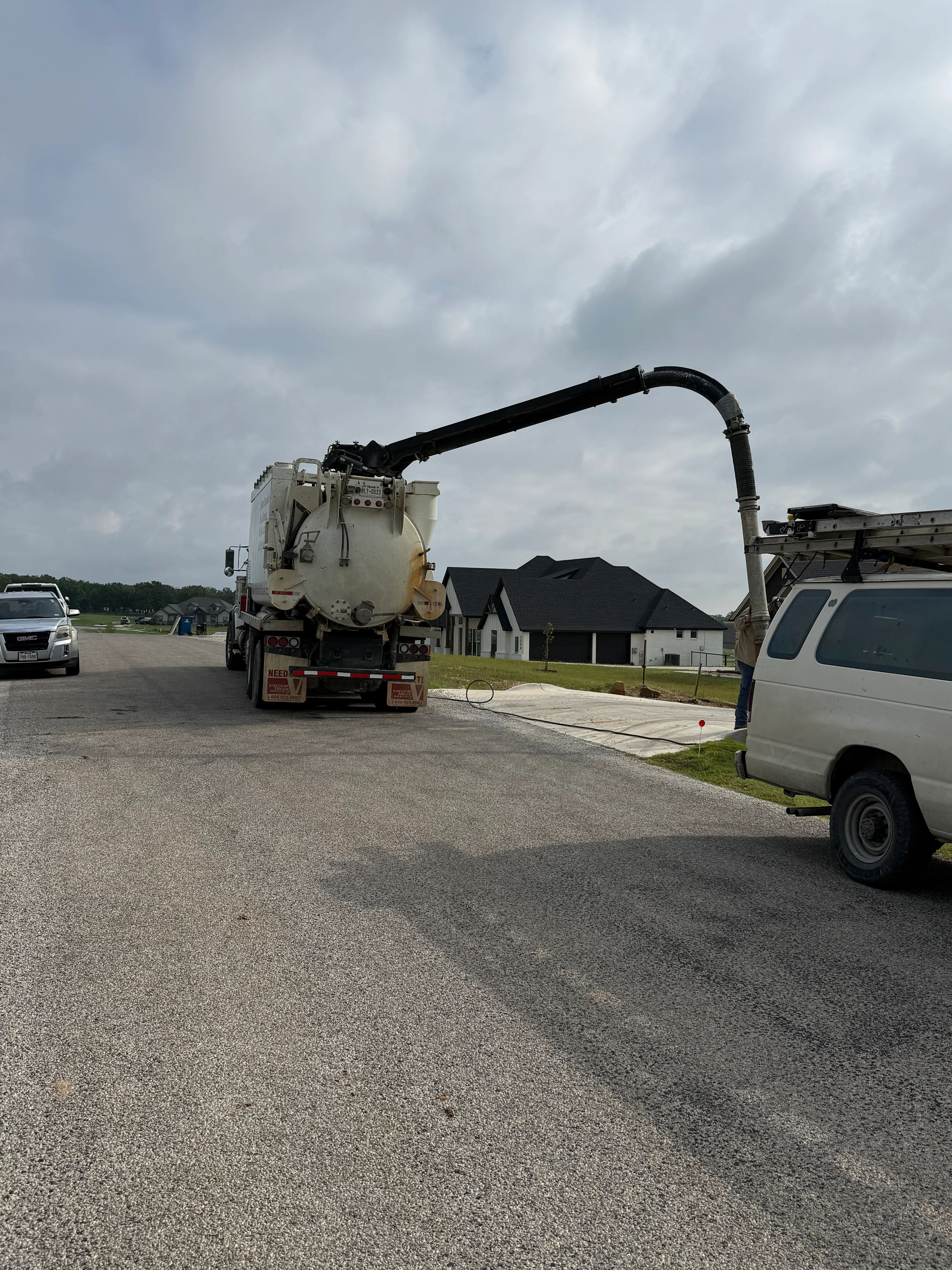 Septic vacuum truck with articulating boom servicing residential property in Weatherford
