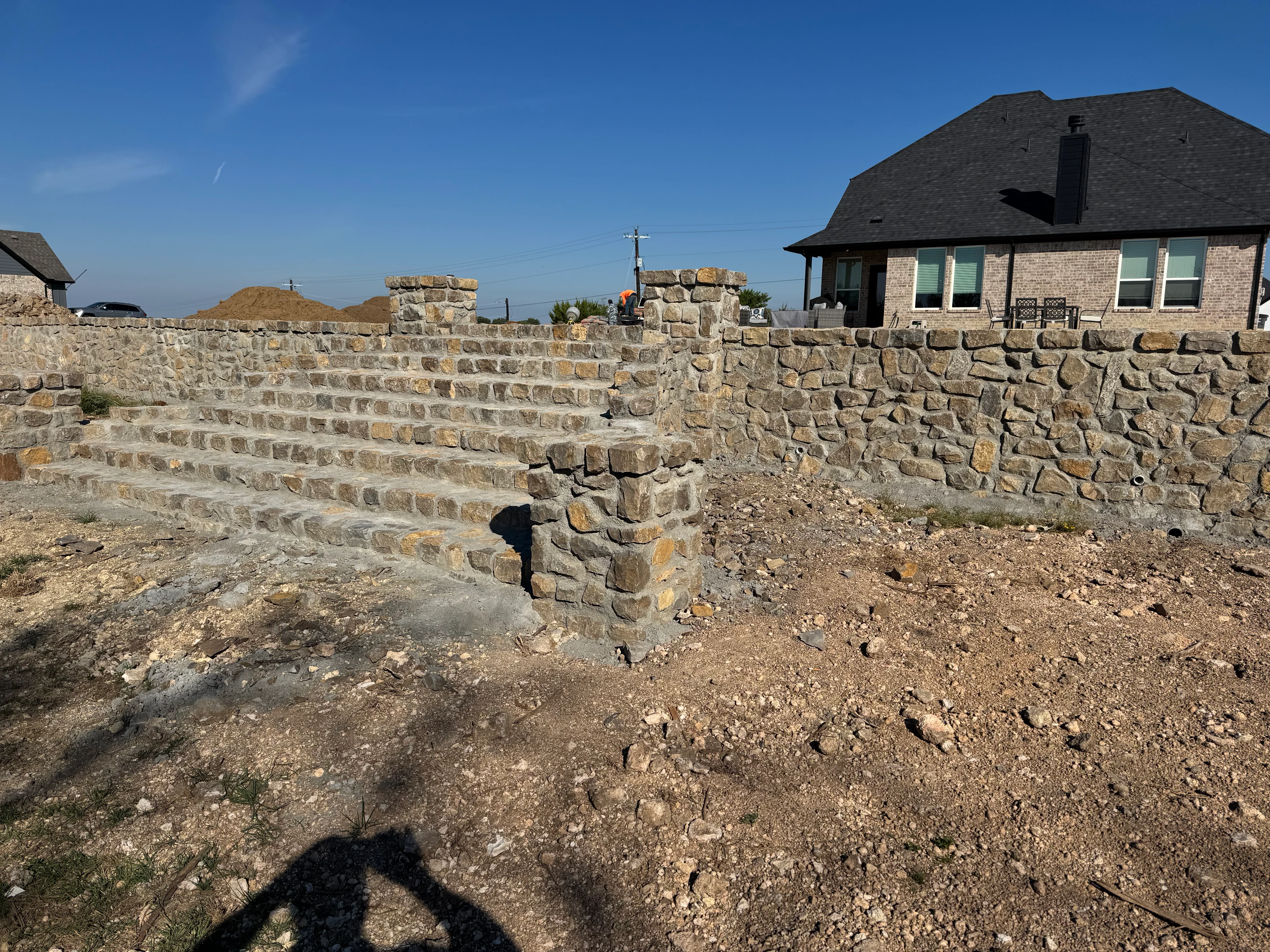 Multi-tiered stone retaining wall with stacked limestone blocks on residential property