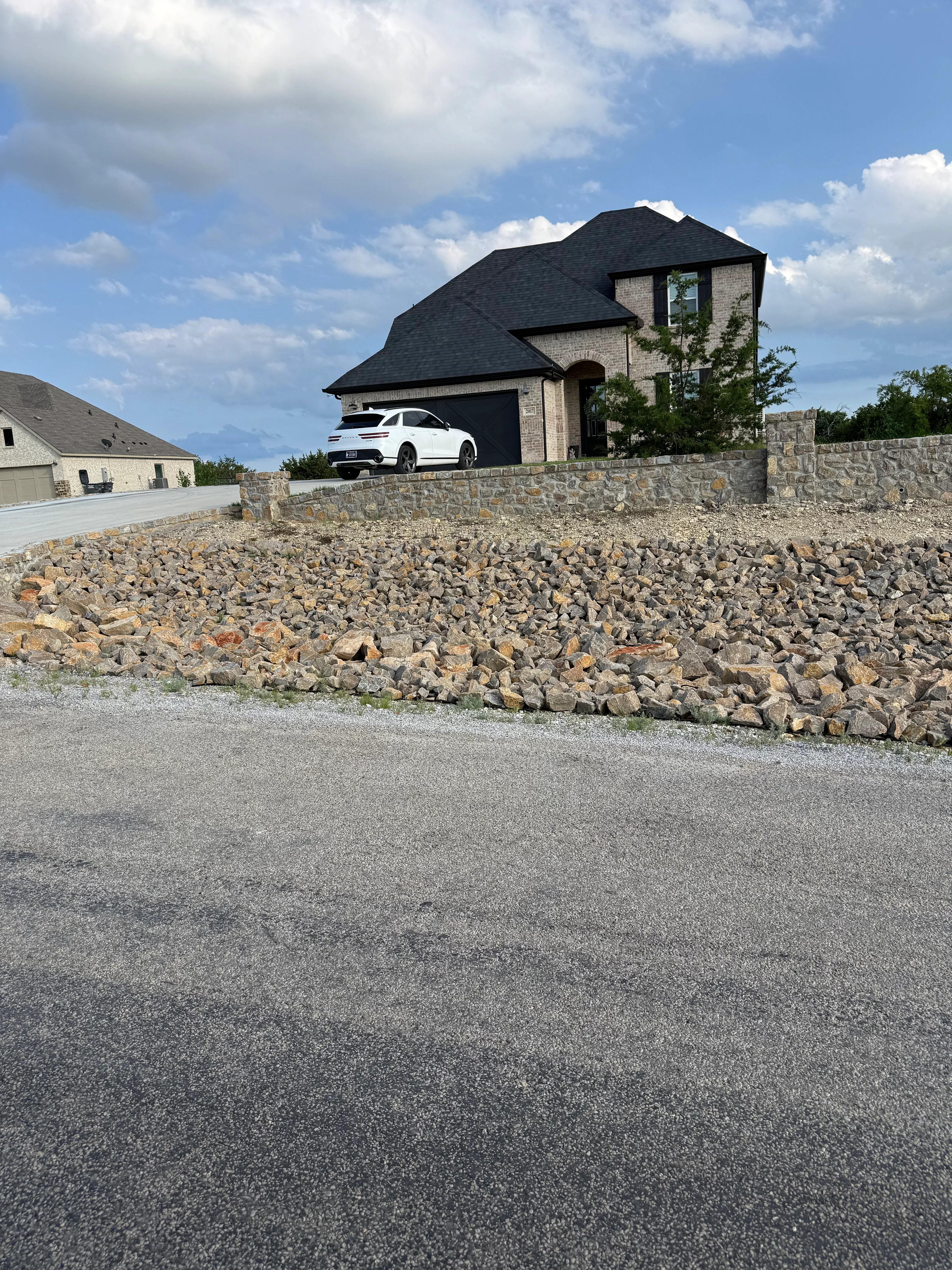 New asphalt driveway with stone retaining wall at residential home in Weatherford