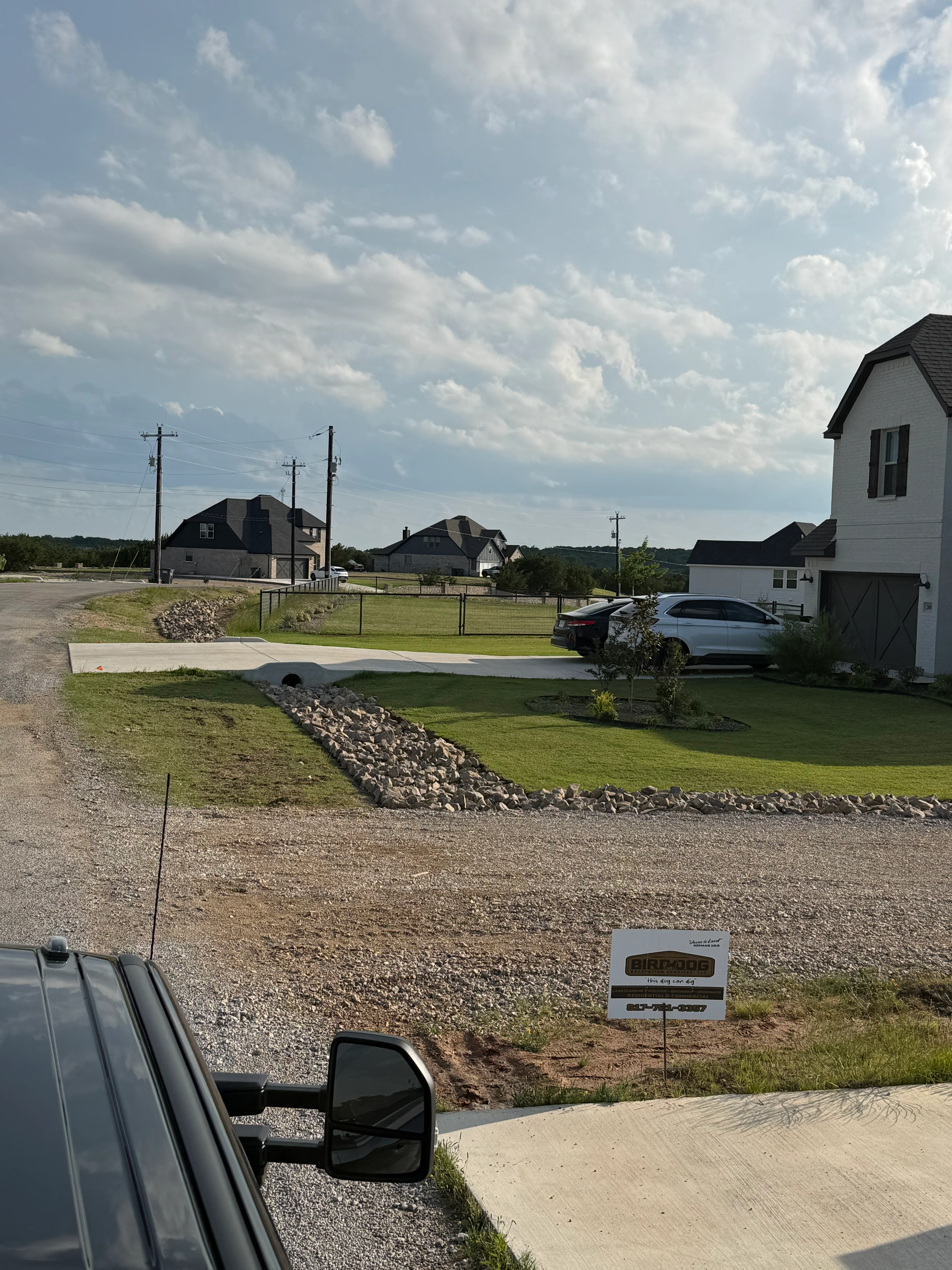 Completed concrete driveway with gravel base and landscape grading on residential lot