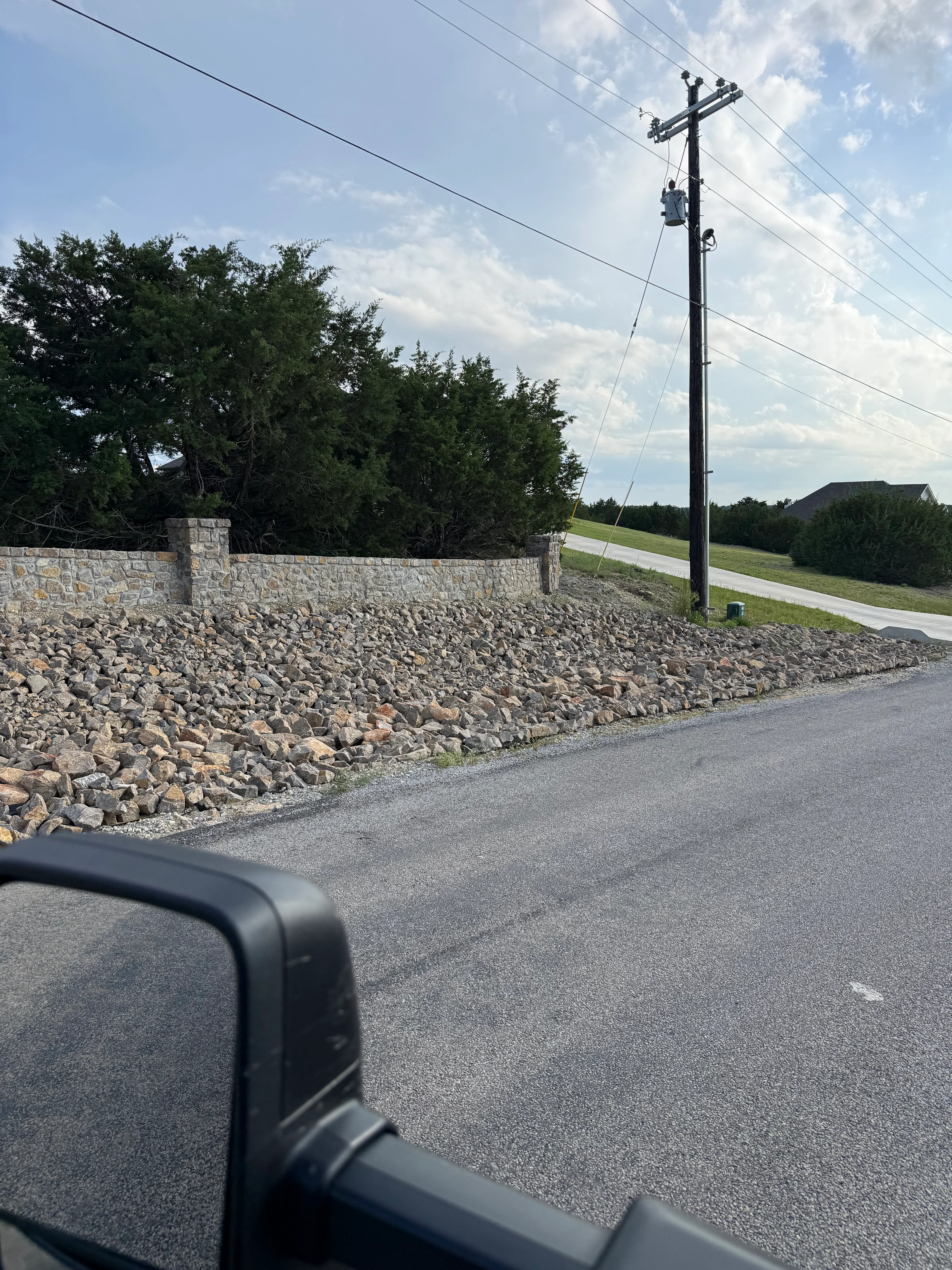 Stone retaining wall with limestone blocks and new asphalt driveway in rural setting